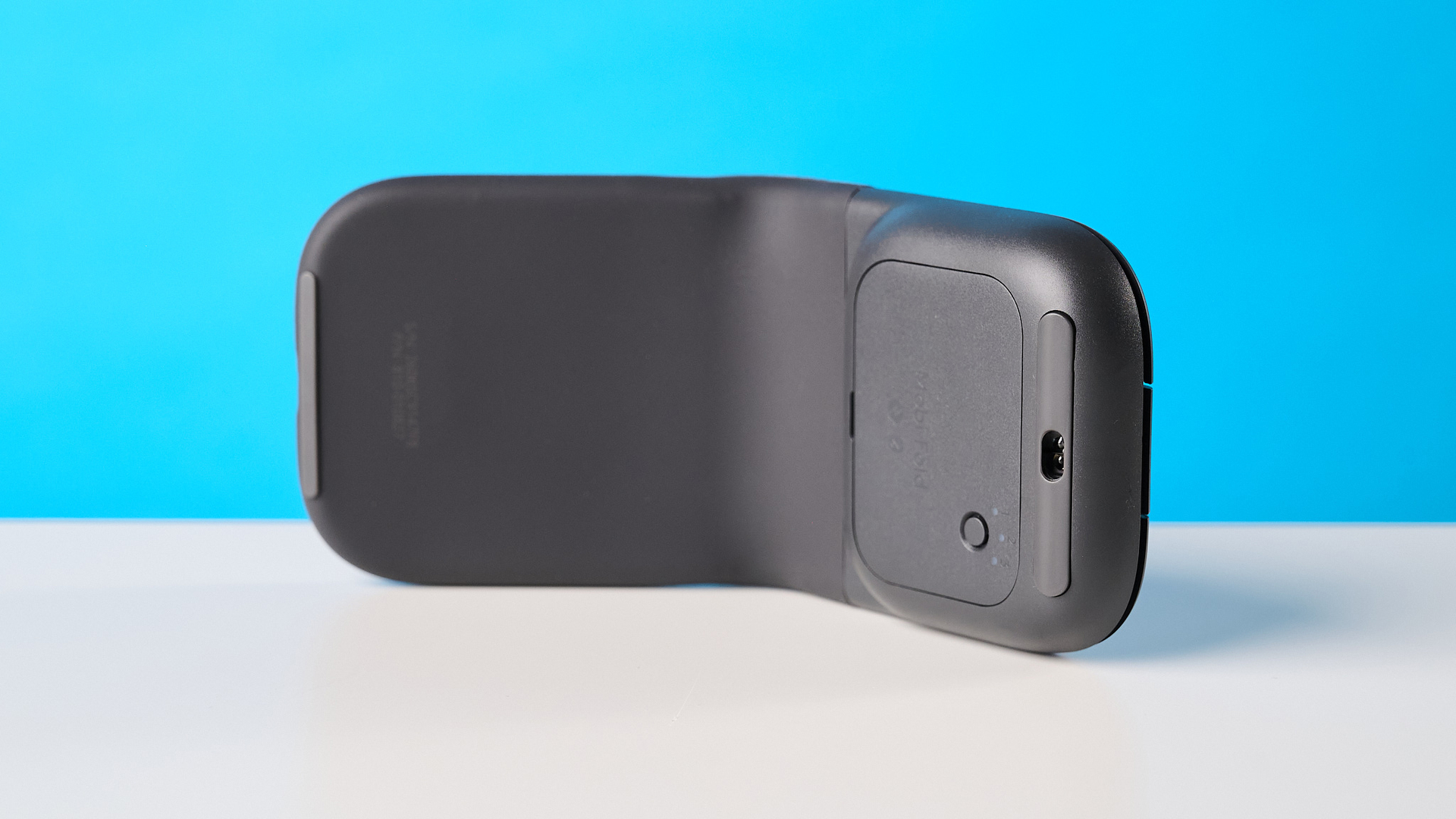 עכבר Logitech Mobi Fold בגרפיט מצולם מול רקע כחול