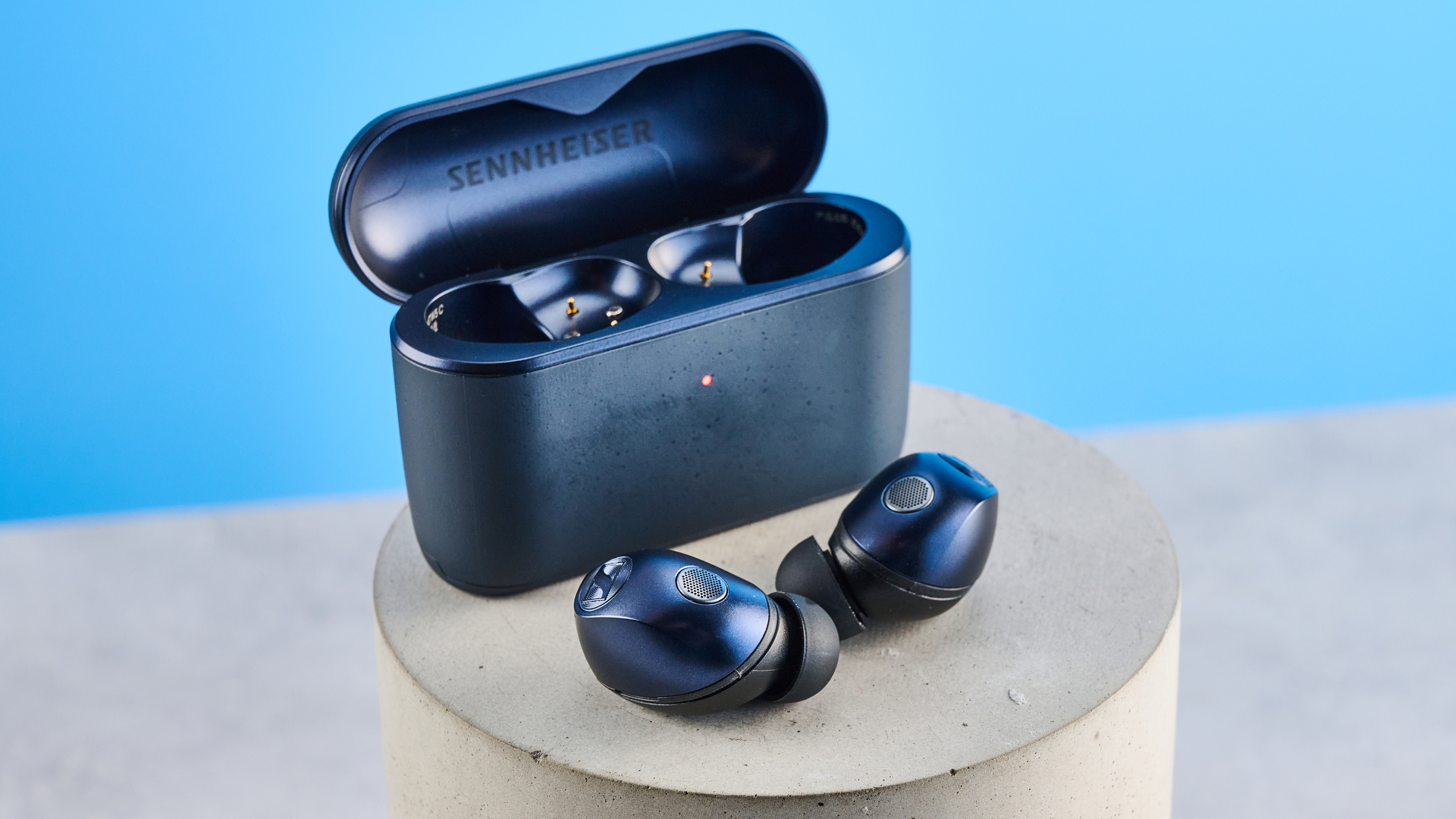 ה- Sennheiser momentum 5 אוזניות אלחוטיות אמיתיות בצבע כחול מצולמים עם רקע המדריך הכחול של Tom's