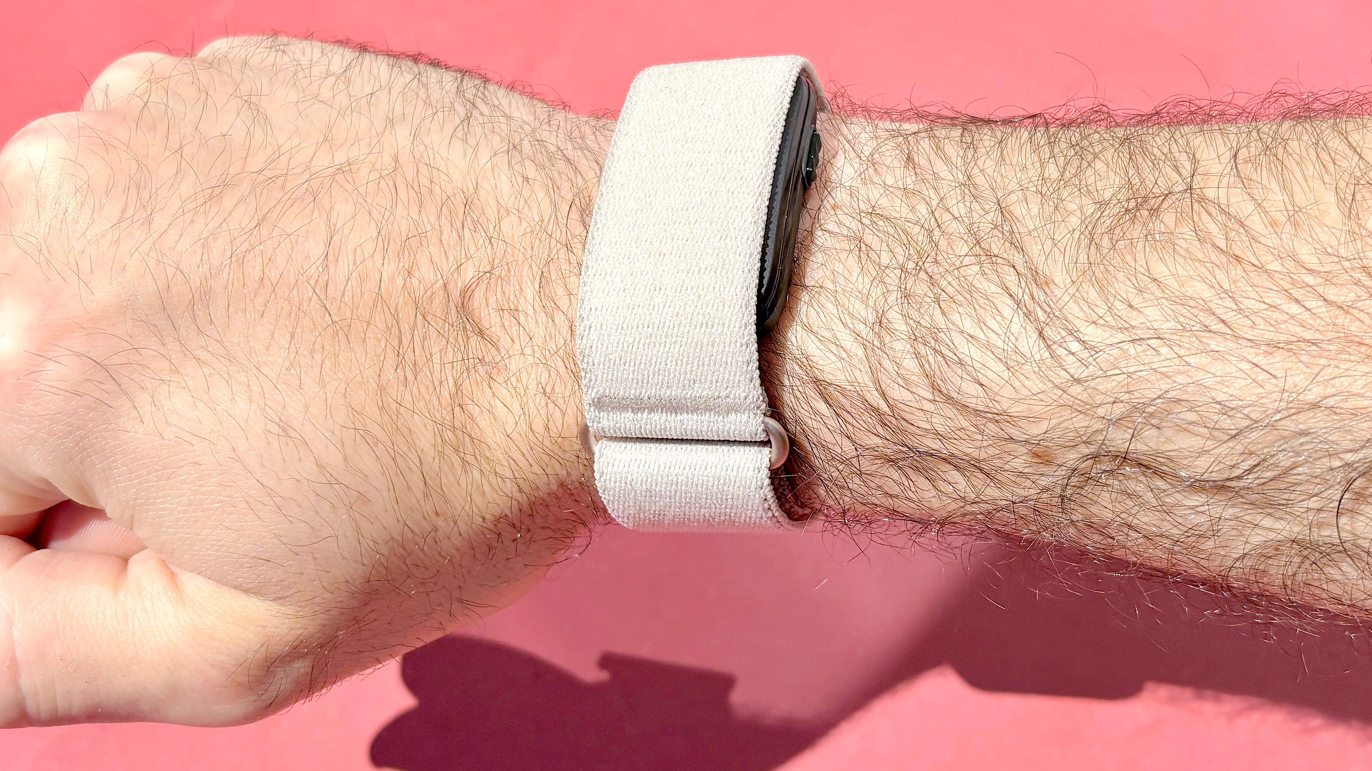 תקריב של Garmin Cirqa על פרק כף היד של הסופר על רקע אדום