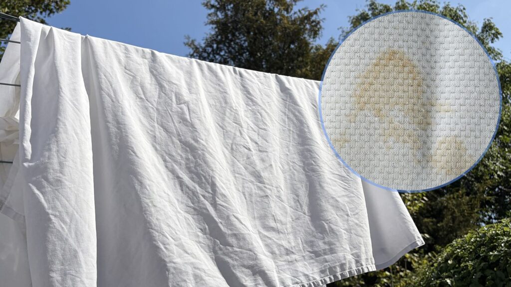 The main image shows a white duvet cover on a washing line on a sunny day. In the top right corner is an ident showing a close up of a yellow stain on bedding