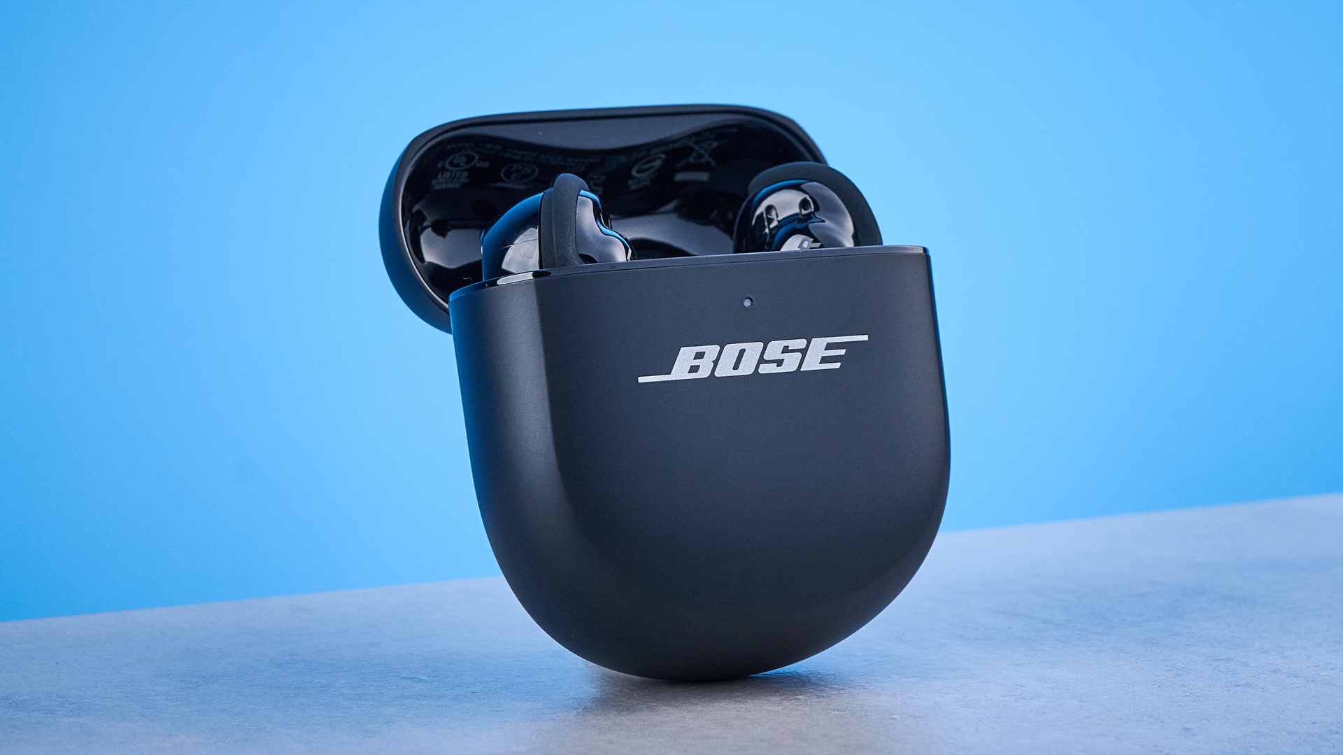 אוזניות ה-Bose Quietcomfort Ultra דור שני על רקע המדריך הכחול