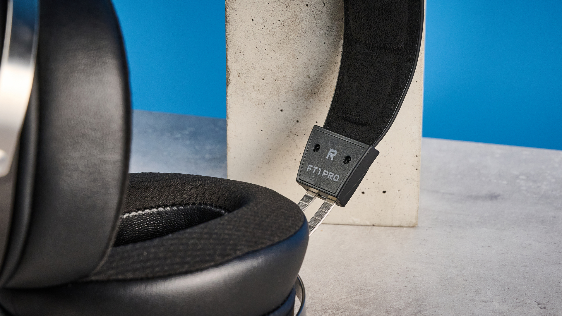 אוזניות ה-fiio ft1 pro חוטיות עם גב פתוח שצולמו עם רקע כחול של מדריך טום