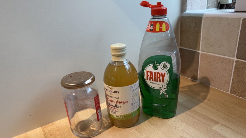 Apple cider vinegar, dish soap and a mason jar on a countertop