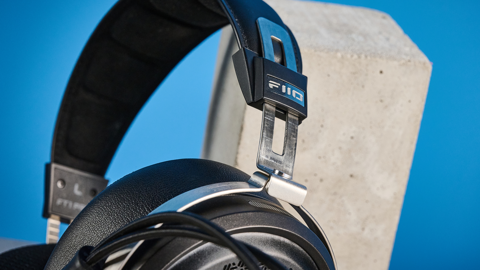 אוזניות ה-fiio ft1 pro חוטיות עם גב פתוח שצולמו עם רקע כחול של מדריך טום