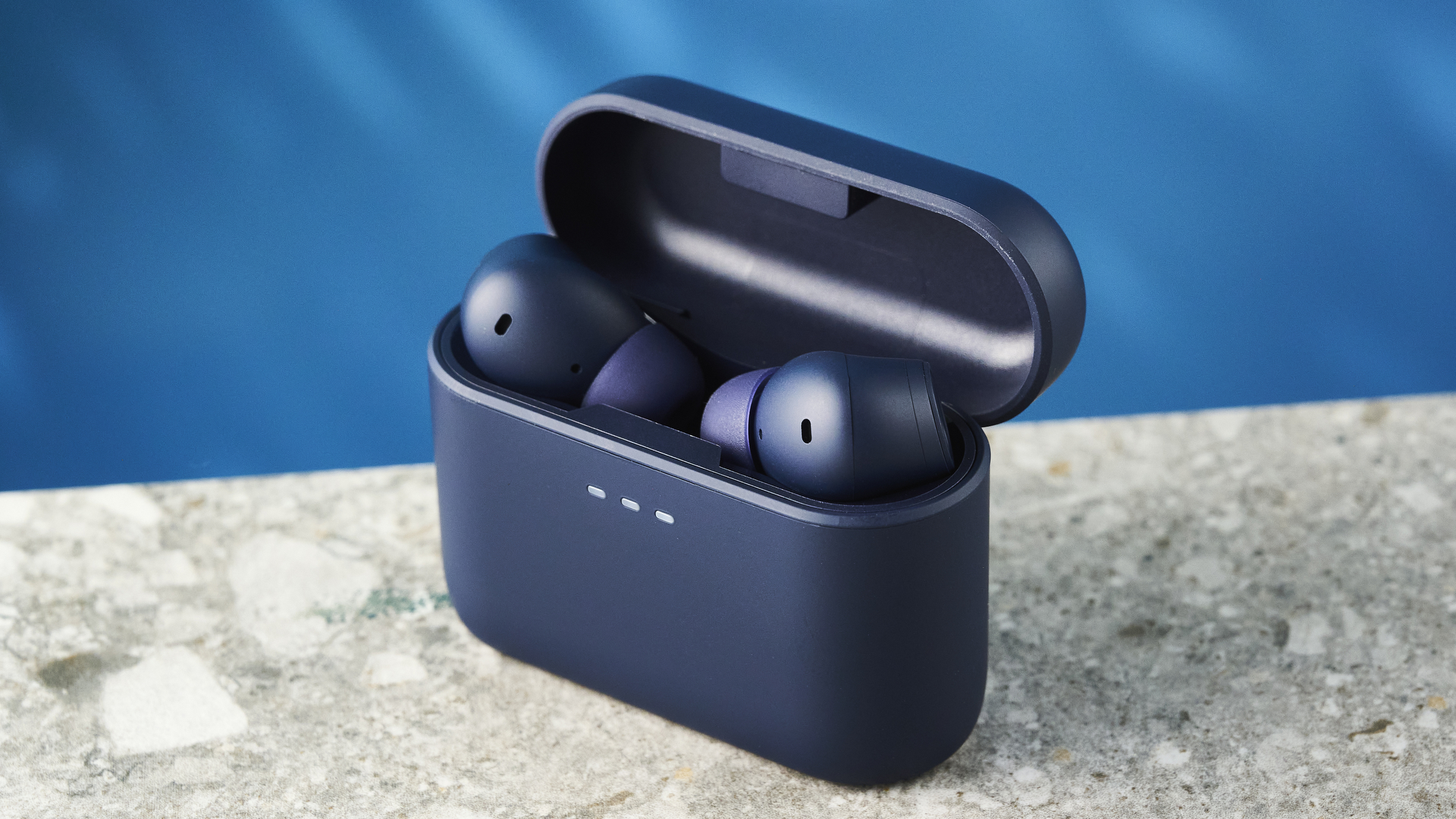 האוזניות של cambridge audio a100 se על רקע מדריך כחול עם שולחן בצבע אבן מתחת