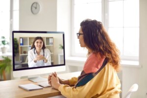 Sick woman listening recommendations and appointment having online video call with a female friendly smiling doctor using pc computer at home.