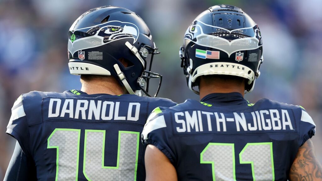 Sam Darnold #14 and Jaxon Smith-Njigba #11 of the Seattle Seahawks standing side-by-side during an NFL game.