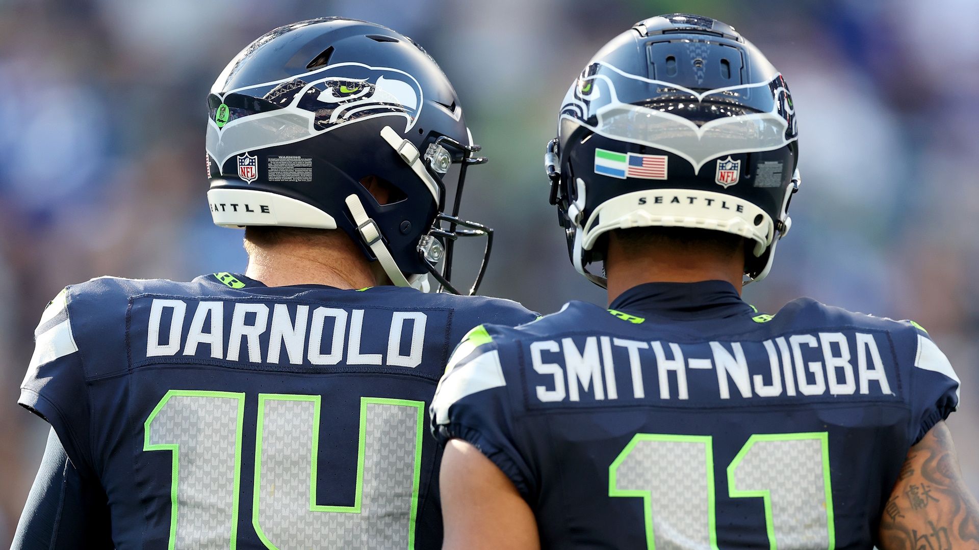 Sam Darnold #14 and Jaxon Smith-Njigba #11 of the Seattle Seahawks standing side-by-side during an NFL game.