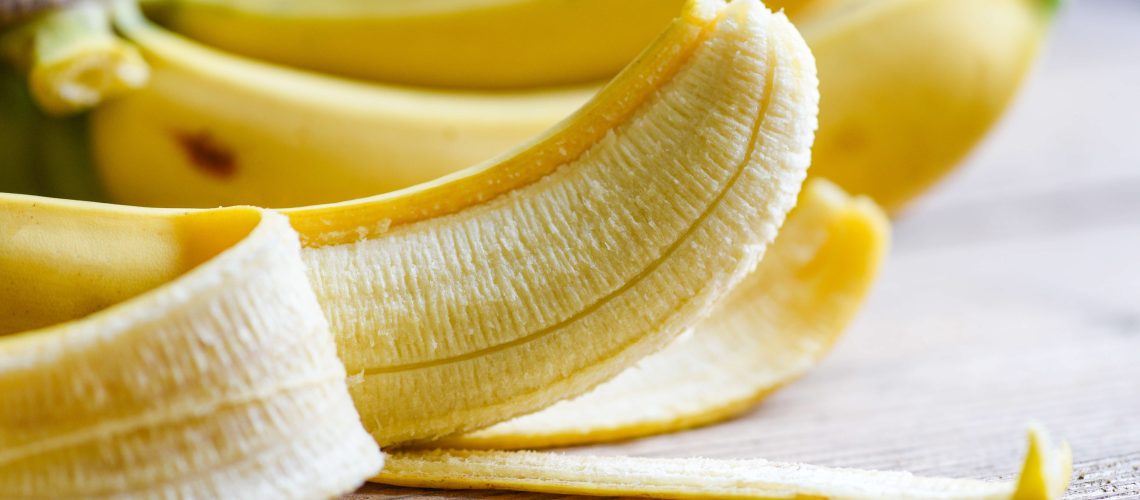 Several bananas with one in foreground peeled