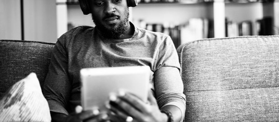 A man reads an iPad while wearing headphones