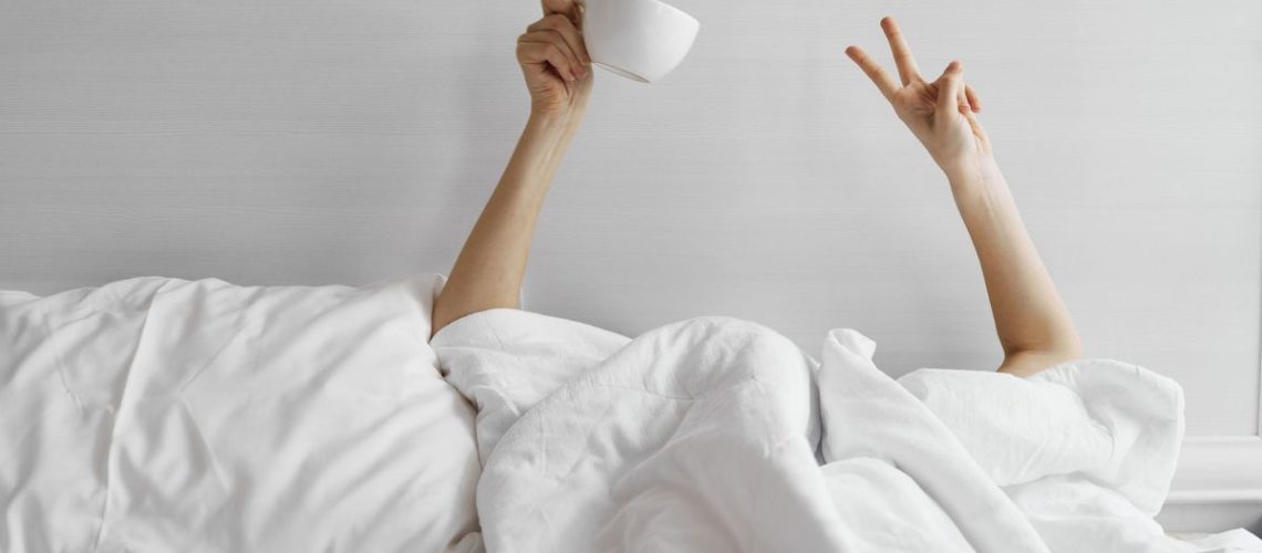 A woman takes a coffee nap in her bed