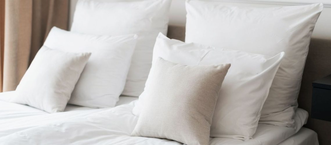 How to make your bed the Scandinavian Sleep Method way image hows two single white duvets and six white pillows placed on a mattress