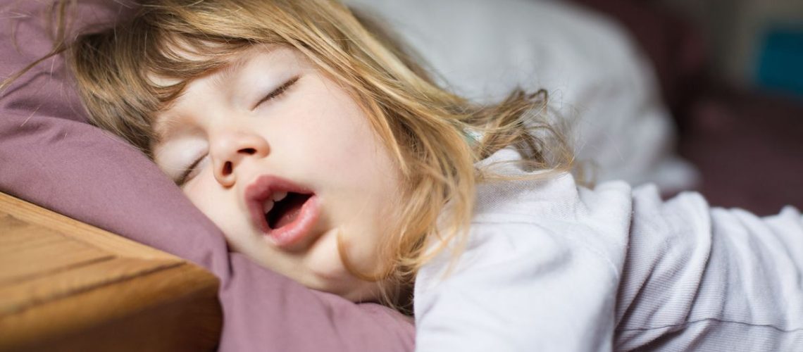 A little girl with blonde hair snores during sleep