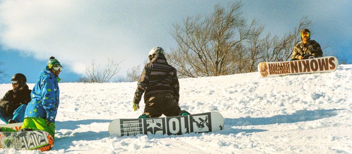 A group of snowboarders hanging out and having fun on the mountain.