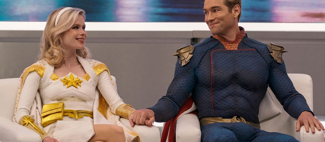 Erin Moriarty (Annie January aka Starlight) and Antony Starr (Homelander), holding hands as they look into each others eyes on a TV talk show in The Boys season 3