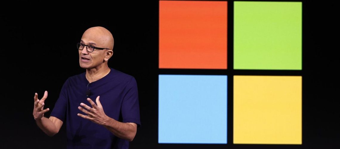 Microsoft CEO Satya Nadella in front of the Windows logo