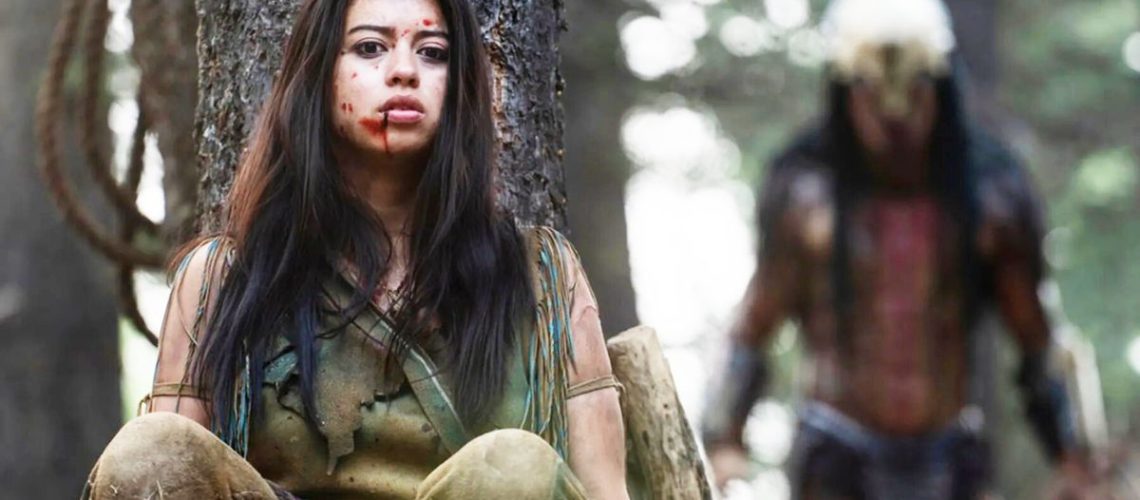 Amber Midthunder as Naru, hiding behind a tree with the Predator behind her in Prey movie on Disney Plus