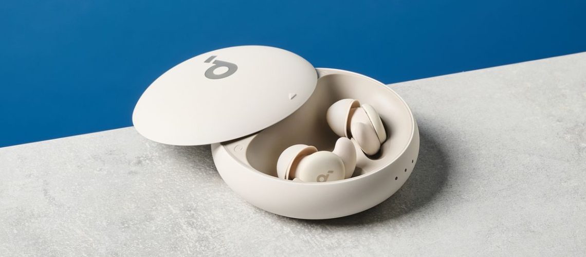 A photo of the Soundcore Sleep A20 earbuds out of and next to their case on a stone surface with a blue wall in the background.