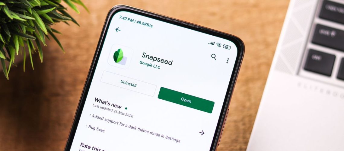 Google Snapseed app shown on the Google Play Store on an Android phone in front of a laptop keyboard