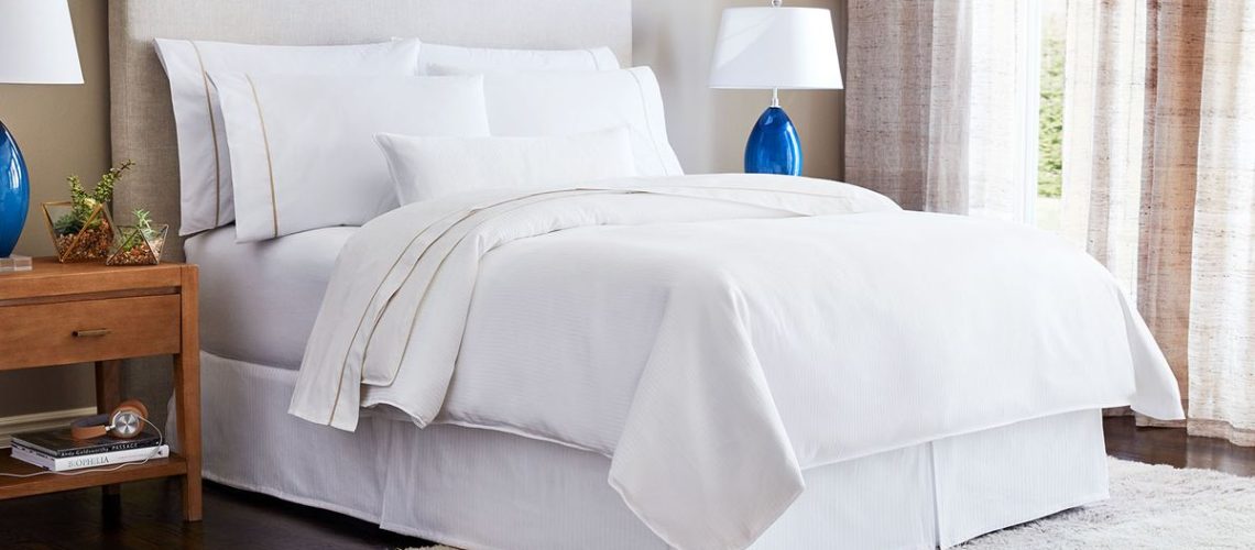 The Westin Heavenly Bed in a hotel bedroom, made up with sheets, comforter, pillows, duvet, boudoir pillow, and bed skirt