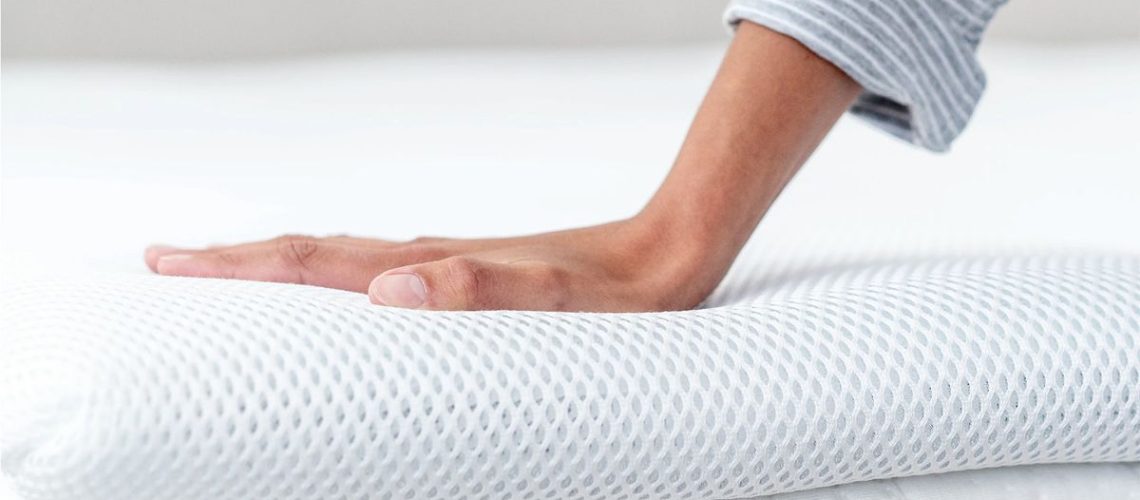 A hand touches the surface of the Perfectly Snug the Smart Topper cooling mattress topper to feel the temperature