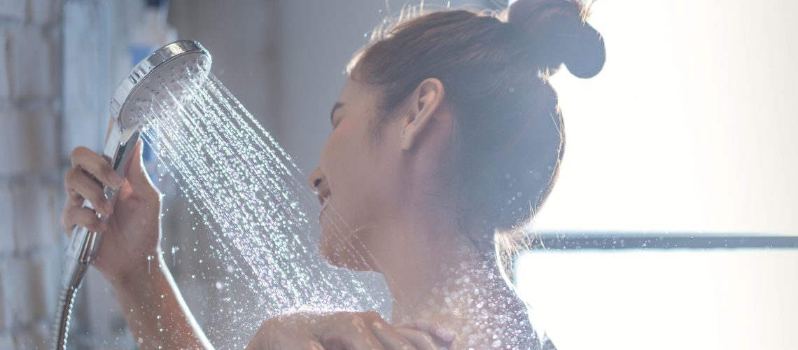 A smiling brunette woman showers in the morning
