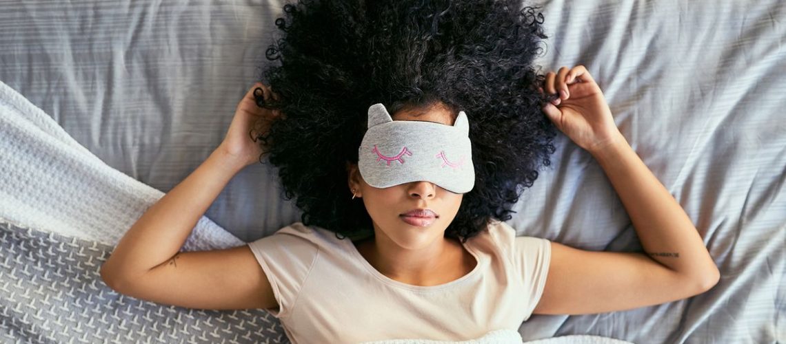 A woman lies in bed sleeping with an eye mask on