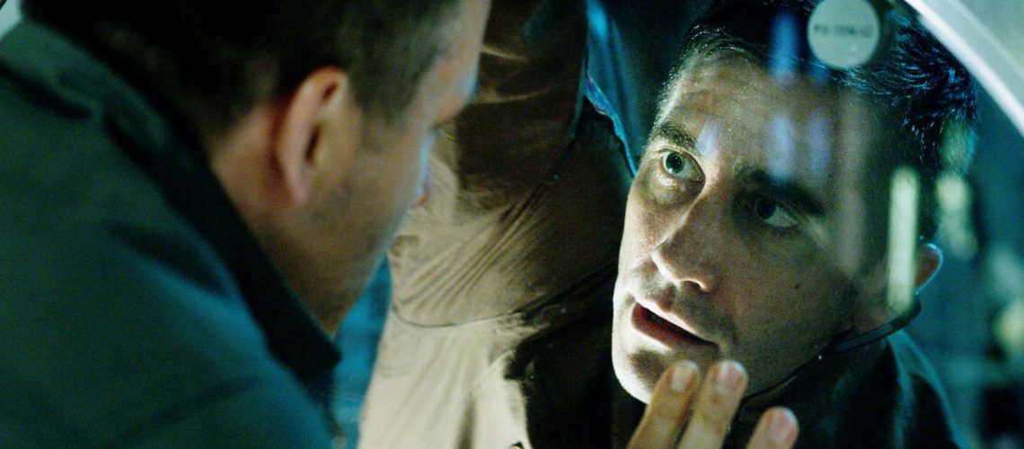 Jake Gyllenhaal peering through a window in