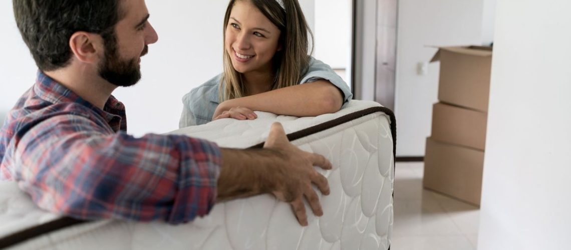 A young couple unbox and move a new memory foam mattress they bought from Amazon during the prime day deals event