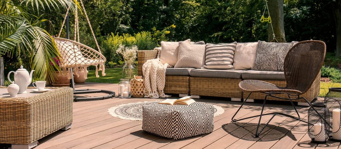 Rattan patio set and furniture on a wooden deck in a sunny garden