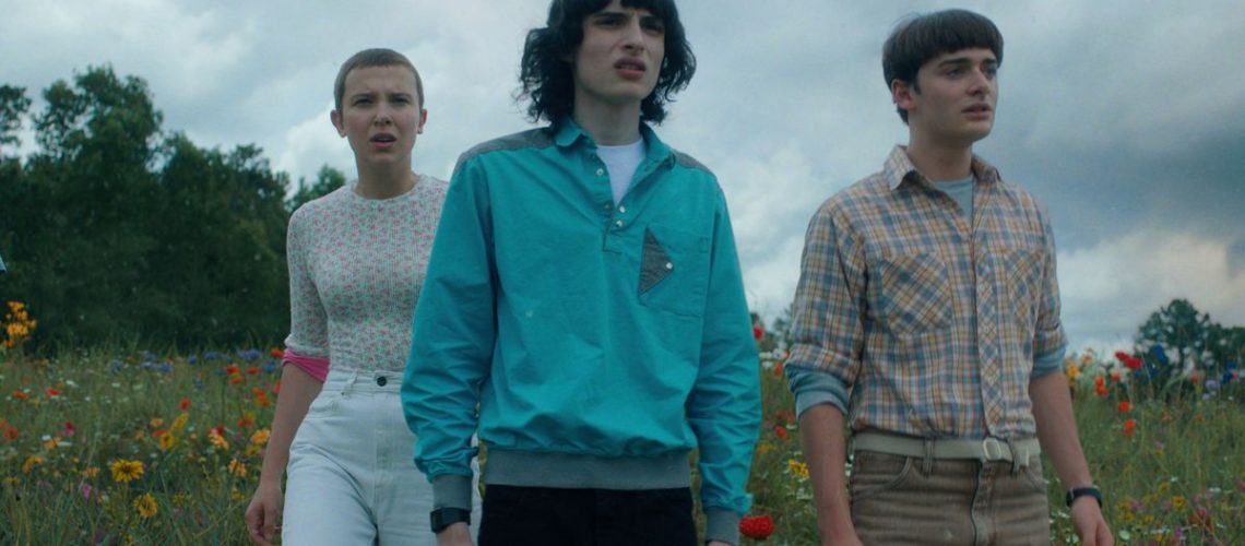 Eleven, Mike, and Will (L-R) stand in a field in