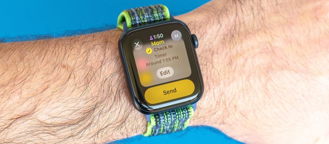 Detail shot of an Apple Watch SE on a bright blue background showing the steps to set up and send a Check In notification in watchOS 11