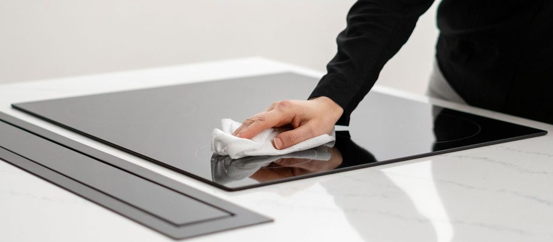 Woman cleaning an ceramic induction cooktop