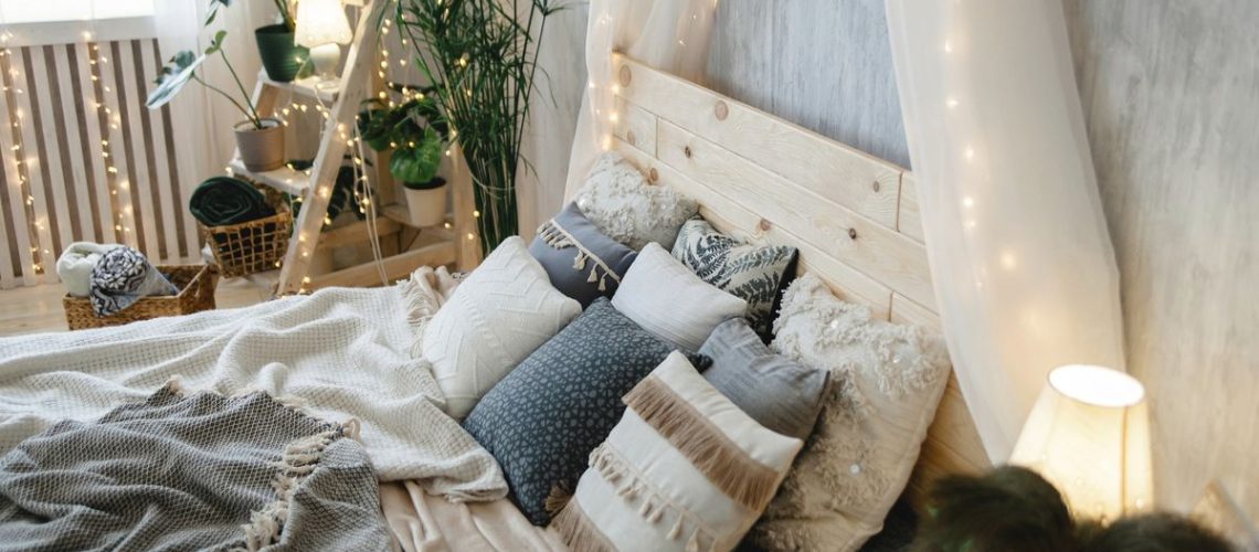 Bed with lots of blankets and pillows on it in a cosy and well decorated bedroom