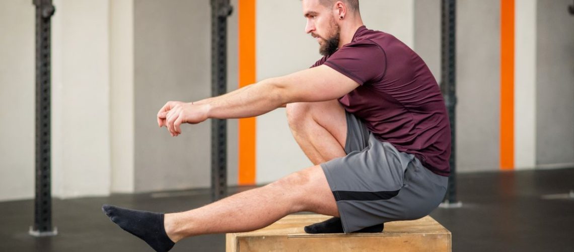 Man performing pistol squat on box at gym
