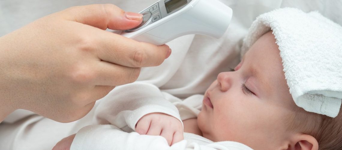 Baby having temperature taken with a forehead thermometer