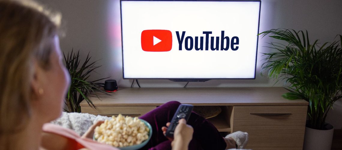 A person watching YouTube on a television with popcorn