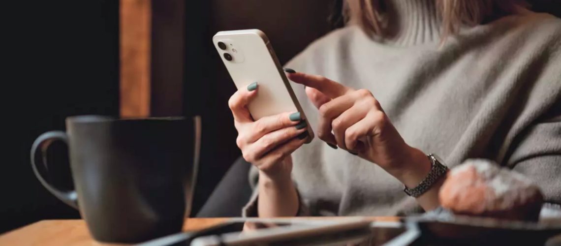 A woman holding an iPhone near an iPad