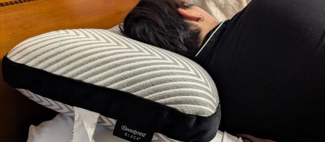 The image shows a woman sleeping on the Beautyrest Black Luxury Foam Pillow