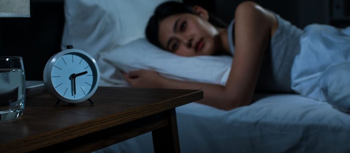 Young woman is wide awake at night and wants to fall back to sleep fast