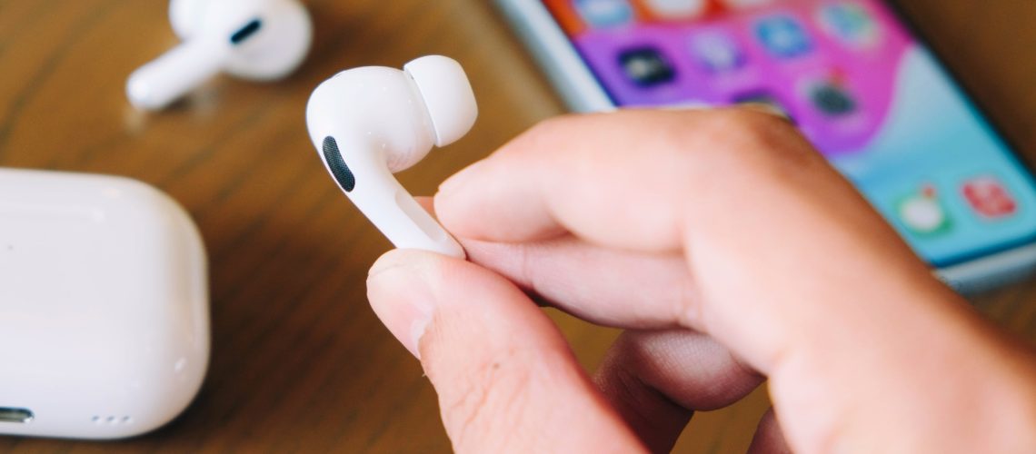 AirPods Pro 2 in hand in front of iPhone
