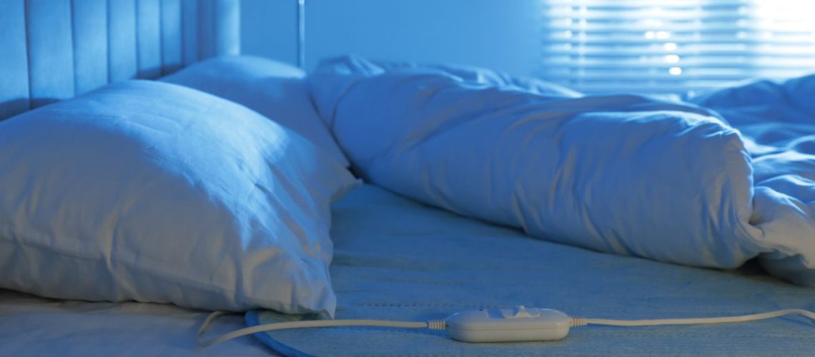 An electric blanket on bed below the duvet