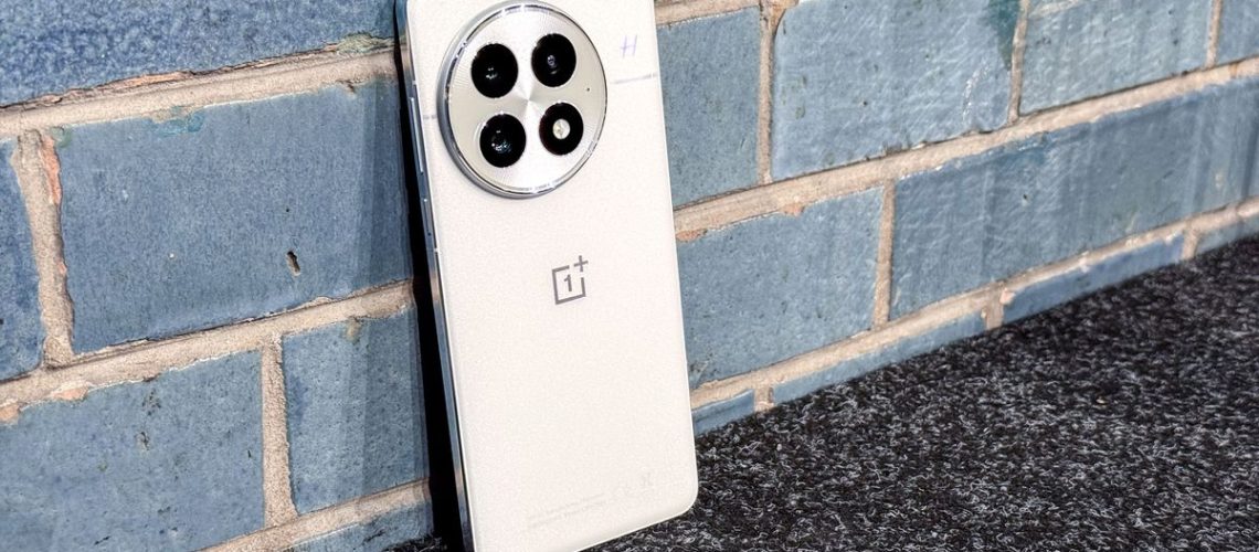 OnePlus 13 back, leaning against blue wall
