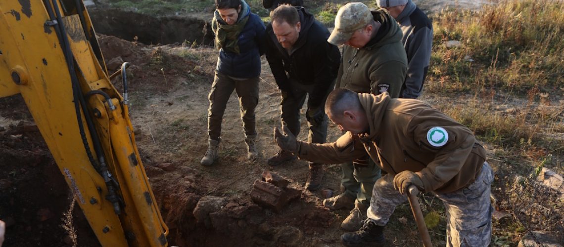 Host Josh Gates, Joanna Lamparska, Krzysztof Mężyk and team watch an excavator dig near a tunnel in Poland as they search for evidence of the Amerikabomber.