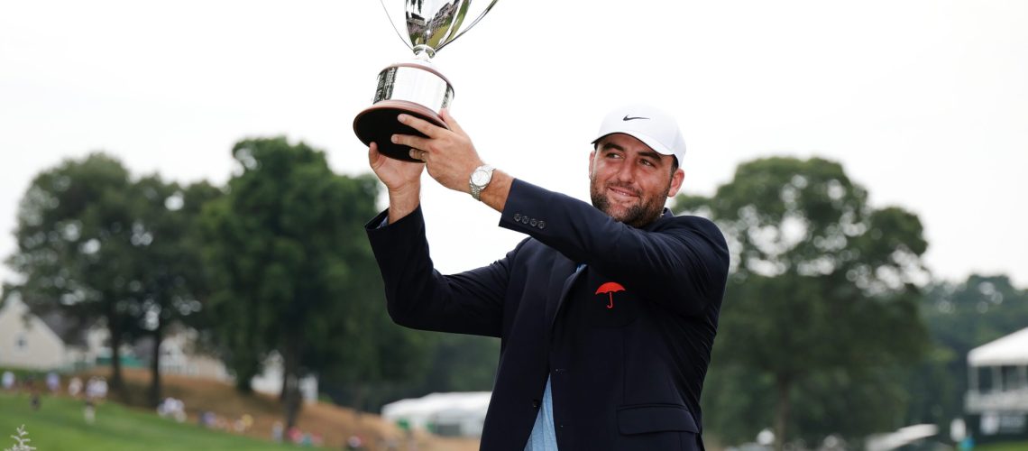 Scottie Scheffler lifts the 2024 Travelers Championship trophy after his victory over Tom Kim in a play-off round.
