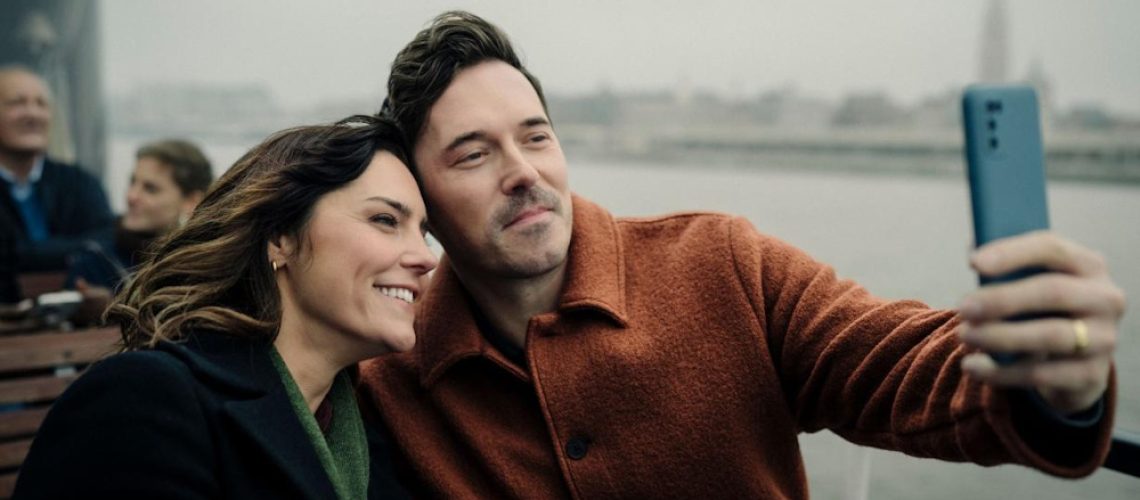 Annabel Scholey as Charlotte and Sam Palladio as Jacob posing for a selfie in a scene from 'The Couple Next Door' season 2.