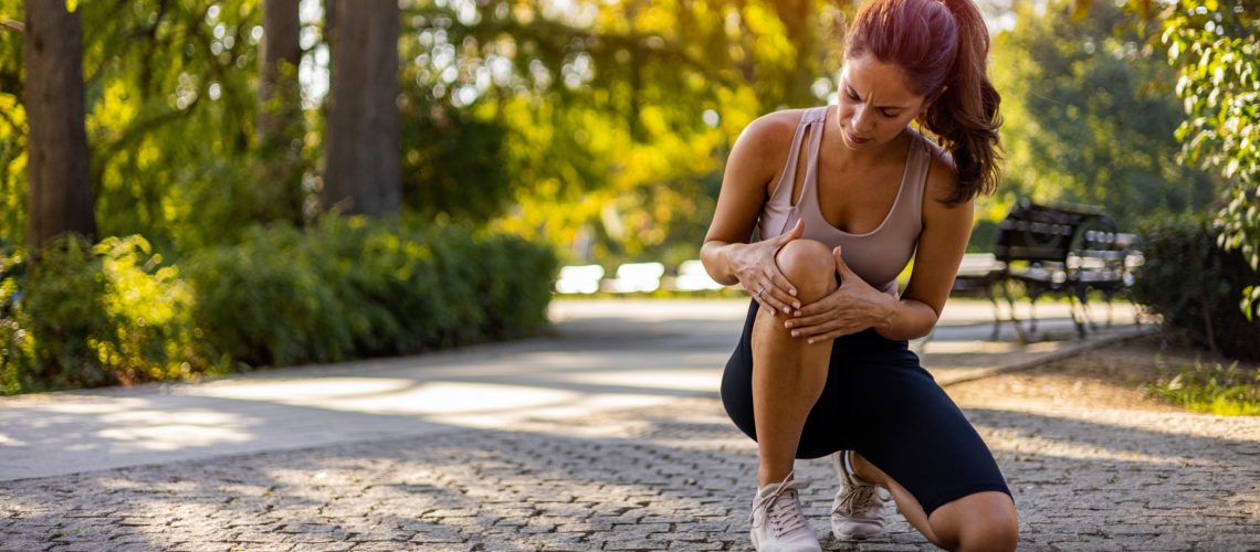 Injured female runner holding knee