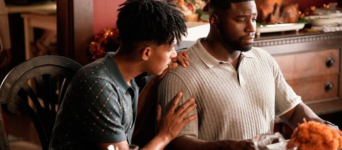 From left to right: Redd (Caleb Eberhardt) comforts Demascus (Okieriete Onaodowan) as they sit down at the dinning table for Thanksgiving dinner in a still from Tubi Original series "Demascus".