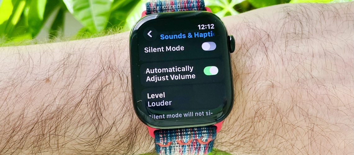 Close-up of a user's wrist wearing the Apple Watch Series 10 running the latest watchOS 26 software. The screen shows the new Automatic Audio Adjustments setting