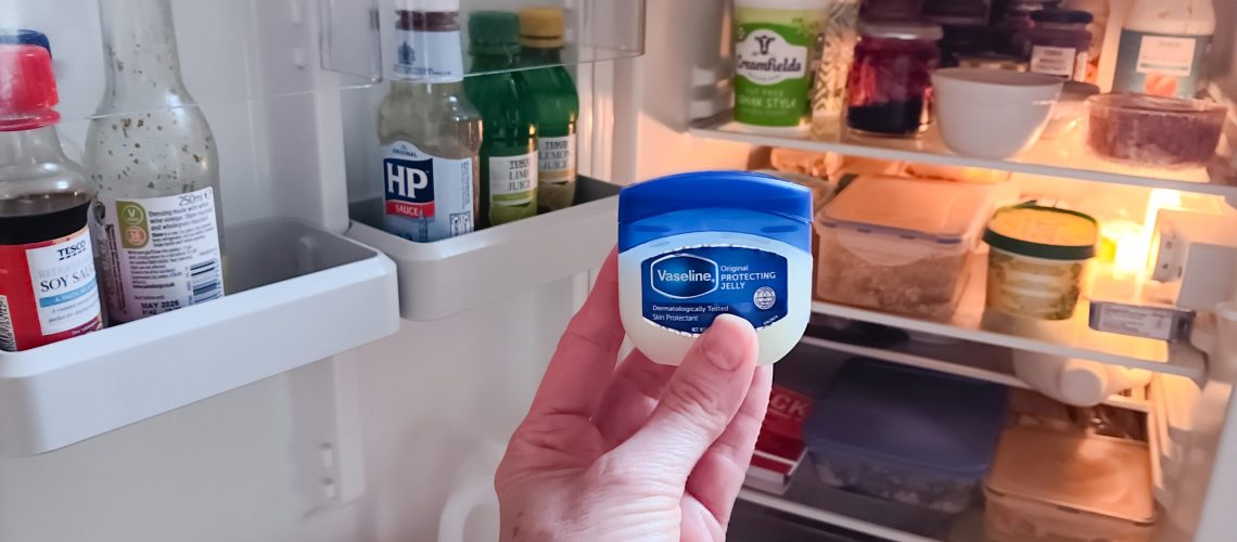 Vaseline being held in front of refrigerator